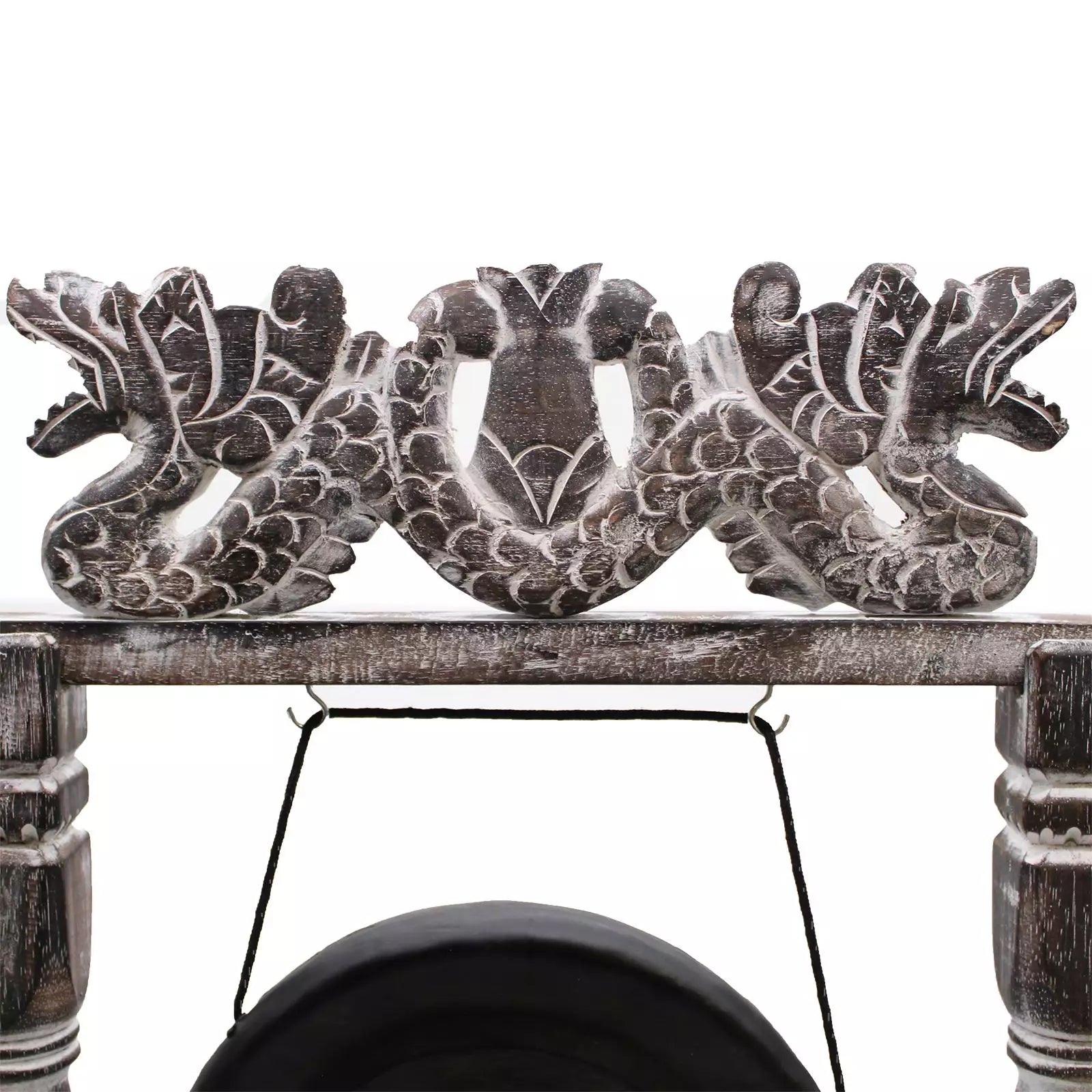 A close-up of a carved wooden decorative piece featuring two dragon figures flanking a central motif, mounted on a rustic wooden beam with a hanging black cord below.