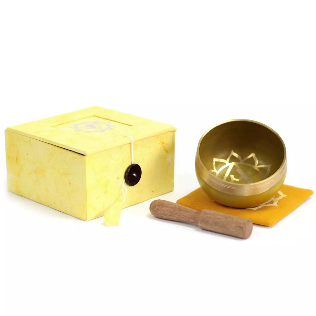 Gold singing bowl set with yellow box and wooden striker on a white background