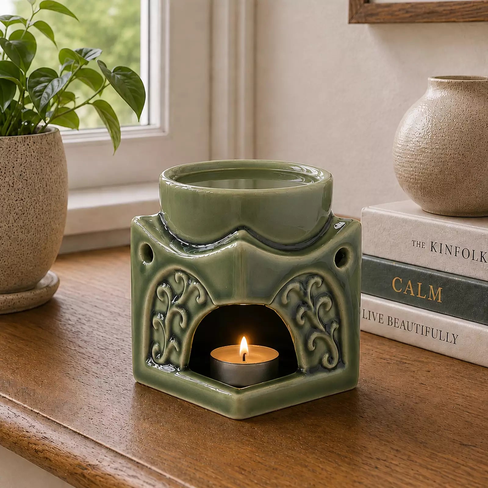 Square Buddha Burner - Dark Jade with intricate carved detailing, holding a lit candle below and a smoking incense cone above, placed on a wooden surface near books and plants.