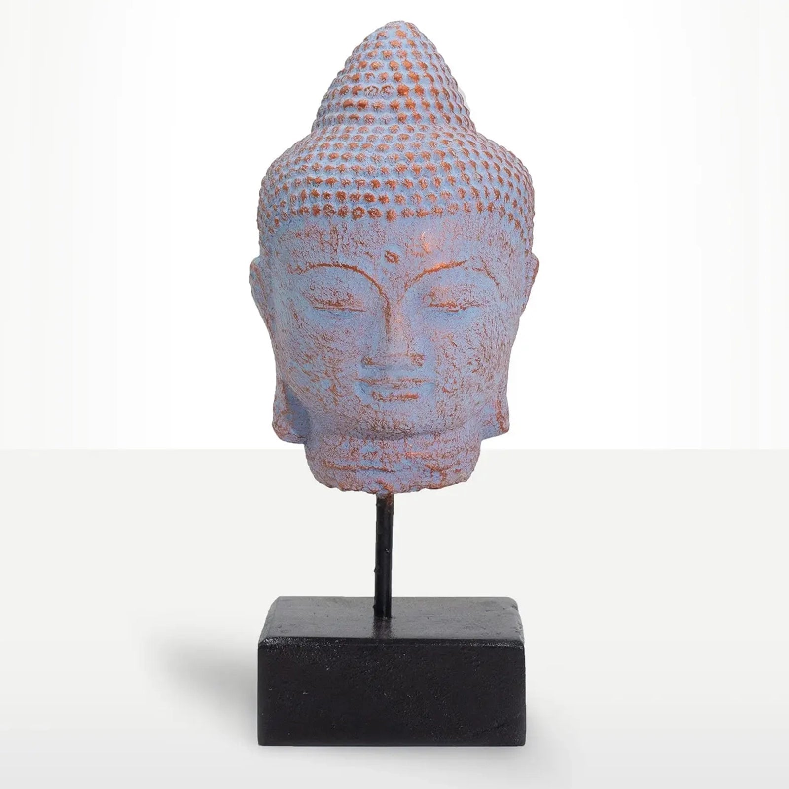 A decorative Buddha head sculpture with a distressed blue and terracotta finish, mounted on a black metal stand with a square black base against a white studio background.