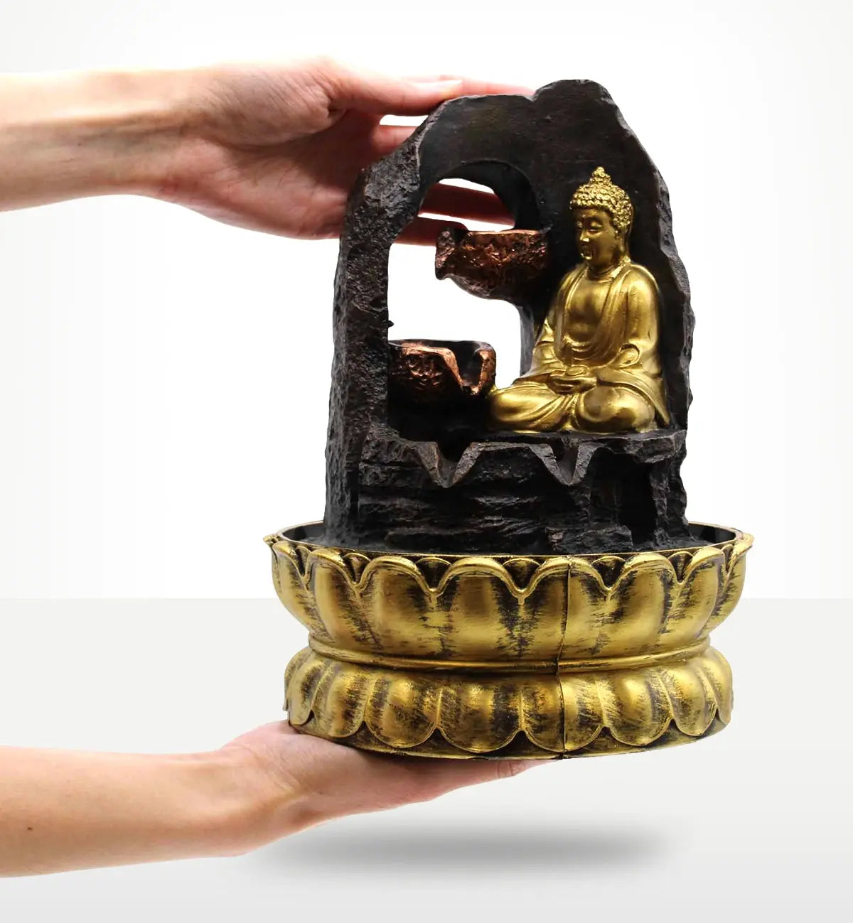 Hands holding a Tabletop Water Feature - 30cm - Golden Meditating Buddha with a carved resin Buddha statue seated inside a stone-like frame above a decorative golden base.