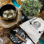 Tibetan singing bowl set with decorative mat and pouch on a wooden surface