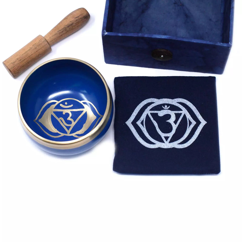 Blue singing bowl set with wooden mallet and pouch featuring a white symbol on a white background
