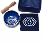 Blue singing bowl set with wooden mallet and pouch featuring a white symbol on a white background