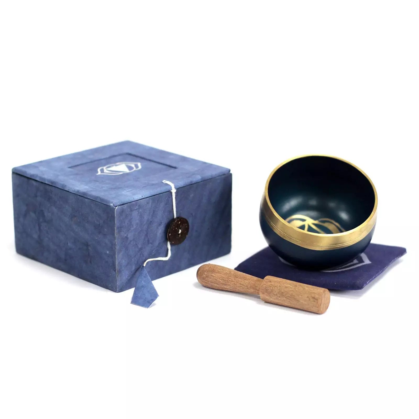 A dark blue singing bowl set with a gold rim, a wooden mallet, a blue fabric cushion, and a textured blue gift box on a white background.