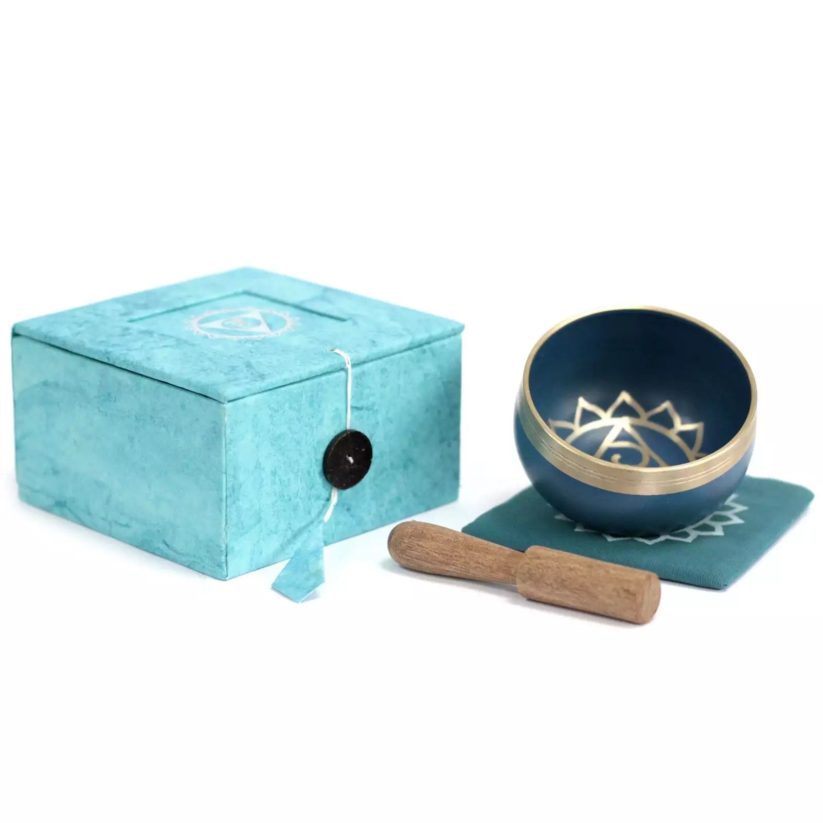Blue singing bowl with gold interior, wooden stick, and turquoise box on a white background