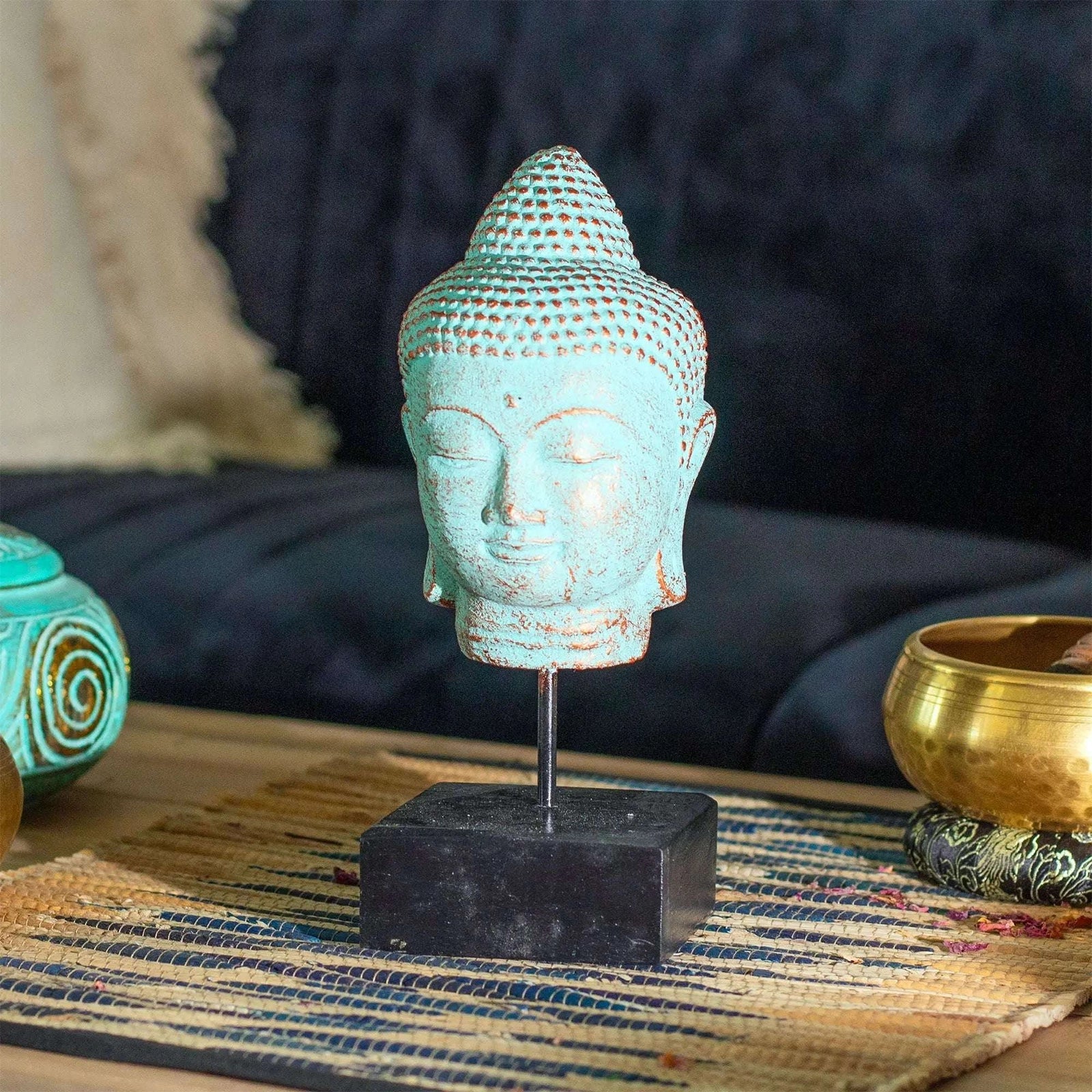 Turquoise Buddha head sculpture on a stand with a blurred background