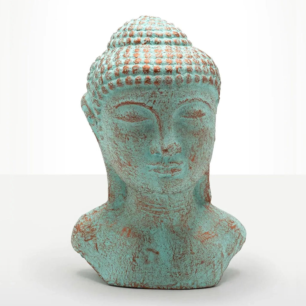 A distressed Buddha head bust sculpture with a turquoise and rust-colored patina, set against a plain white background.