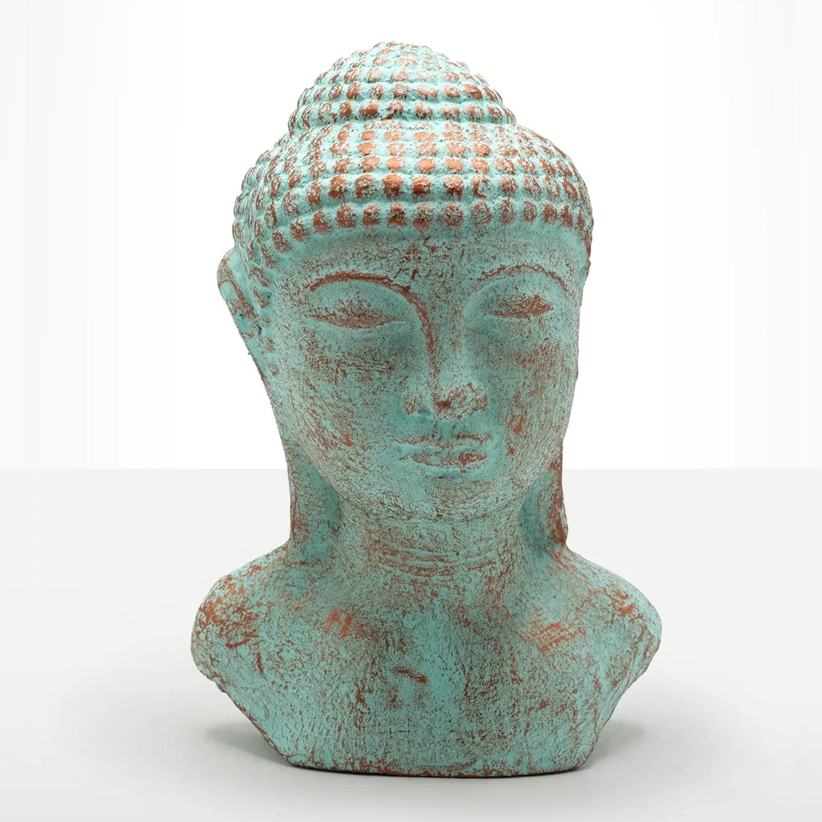 A distressed Buddha head bust sculpture with a turquoise and rust-colored patina, set against a plain white background.
