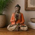 Vintage Orange Hand Carved Buddha Wooden Statue - 40cm - Teaching Transmission seated on a wooden surface, surrounded by natural home decor including a plant and books.
