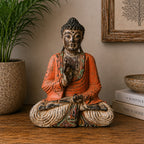 Vintage Orange Hand Carved Buddha Wooden Statue - 40cm - Teaching Transmission seated on a wooden surface, surrounded by natural home decor including a plant and books.