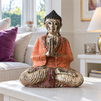 30 cm vintage orange wooden Buddha seated in prayer on a white table in a bright sitting room.