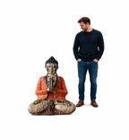Man standing next to a large, vintage orange hand carved wooden Buddha statue in a seated meditation pose, showcasing the detailed craftsmanship and serene design of the 30cm statue titled Vintage Orange Hand Carved Wooden Buddha Statue - 30cm - Welcome.