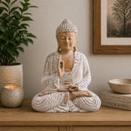 Wooden Buddha Statue Whitewash - 40cm Teaching Transmission seated in meditation pose on a wooden surface, surrounded by a candle, plant, and decorative books in a calm home setting.