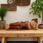 Wooden Sleeping Buddha - 50cm hand carved statue in serene reclining pose, displayed on a wooden table with natural decor including plants and rustic wall art.