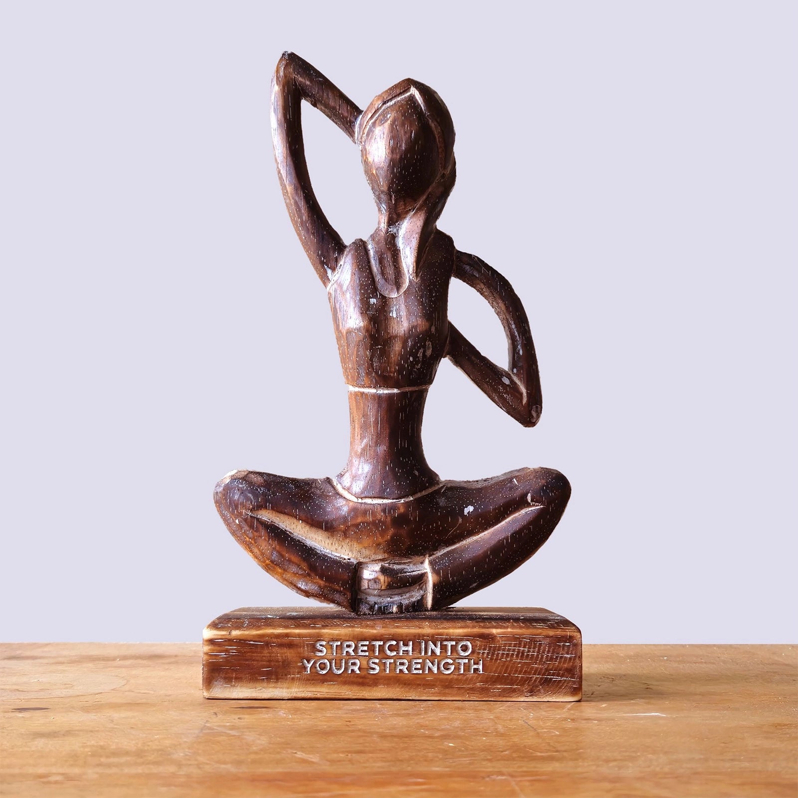 Wooden Yoga Lady - Antique - Cow Face Pose - "Stretch into Your Strength" depicts a hand-carved wooden figure in a seated yoga pose, symbolizing strength and mindfulness.