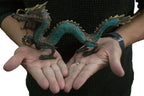 A person holding a detailed Fengshui - Med Dragon with Ball - 27cm sculpture featuring green and bronze tones, showcasing intricate scales and features.