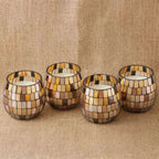 Four Small Glass Jar Candles - Amber Mosaic with warm amber and beige glass tiles arranged in a checkerboard pattern, placed on a textured fabric surface.