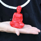 Hand holding a vibrant red Matt Mini Buddha (Assorted Colours) statue, showcasing a small resin Buddha figure perfect for tabletop decor and spiritual accents.