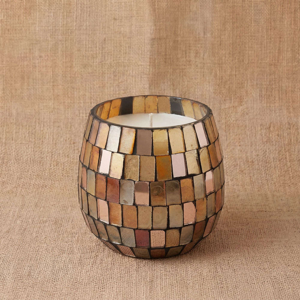 Small Glass Jar Candles - Amber Mosaic featuring a decorative amber and gold mosaic pattern on a glass jar sitting on a textured beige fabric background.