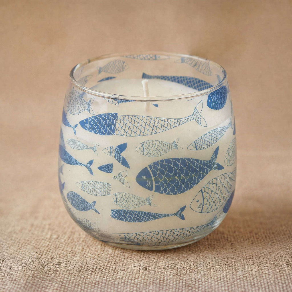 Medium Glass Jar Candles - Seabreeze featuring a clear glass jar decorated with blue fish illustrations on a natural textured surface.
