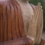 Close-up of hands in prayer position on a Hand Carved Buddha Statue - 80cm Welcome, showcasing detailed wood carving and smooth finish of this Buddha décor piece.