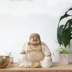 Happy Buddha - Whitewash 30cm handcrafted resin statue with a smiling figure in whitewashed finish, displayed on a wooden surface with potted plants and brass decor.