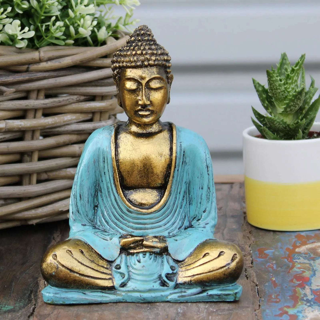 Teal & Gold Buddha - Medium statue with serene facial expression, seated in meditation pose, displayed on rustic wooden surface beside green plants.