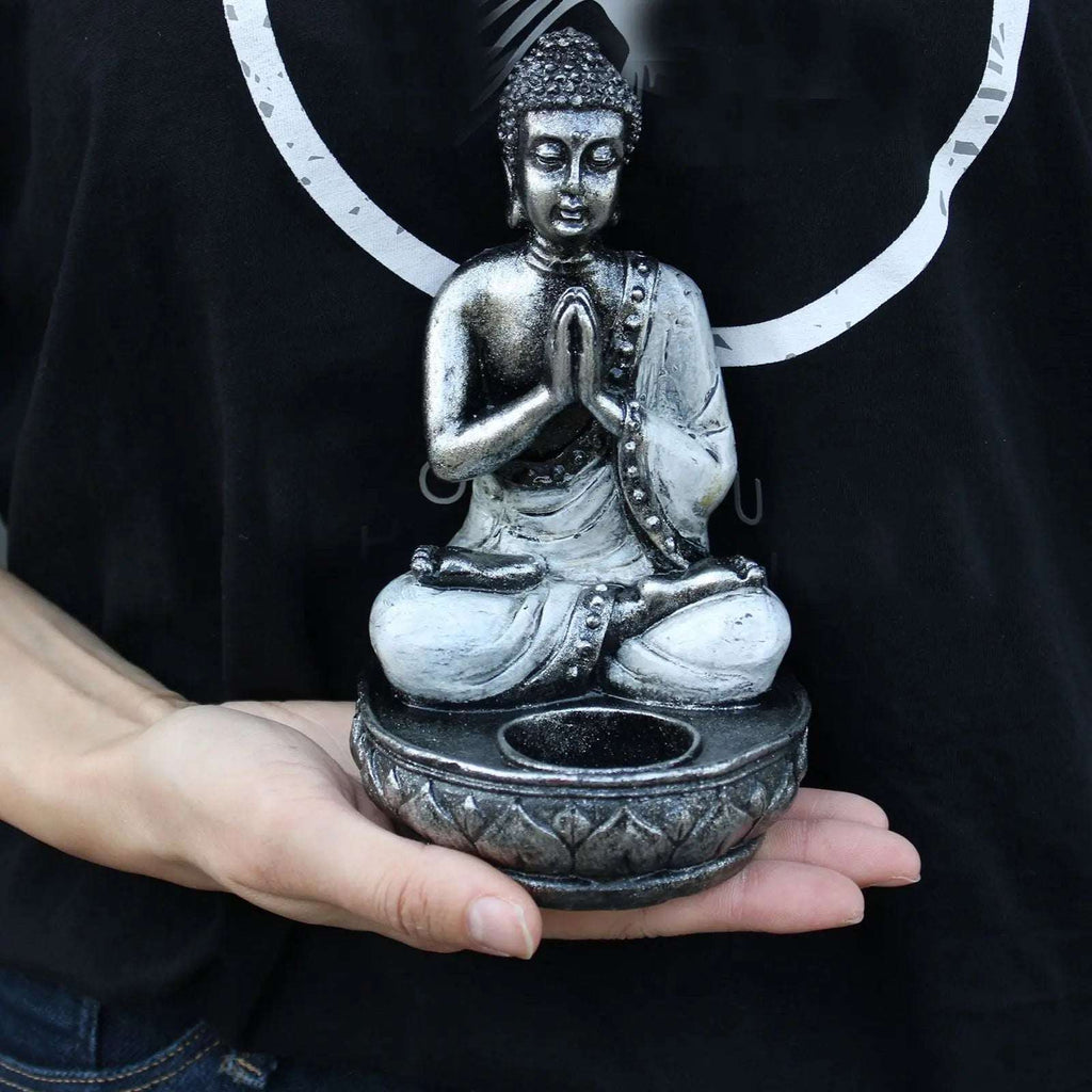 Person holding a Buddha Candle Holder - White - Medium, featuring a detailed meditating Buddha figure in a seated pose with hands in prayer, designed as a decorative candle holder.
