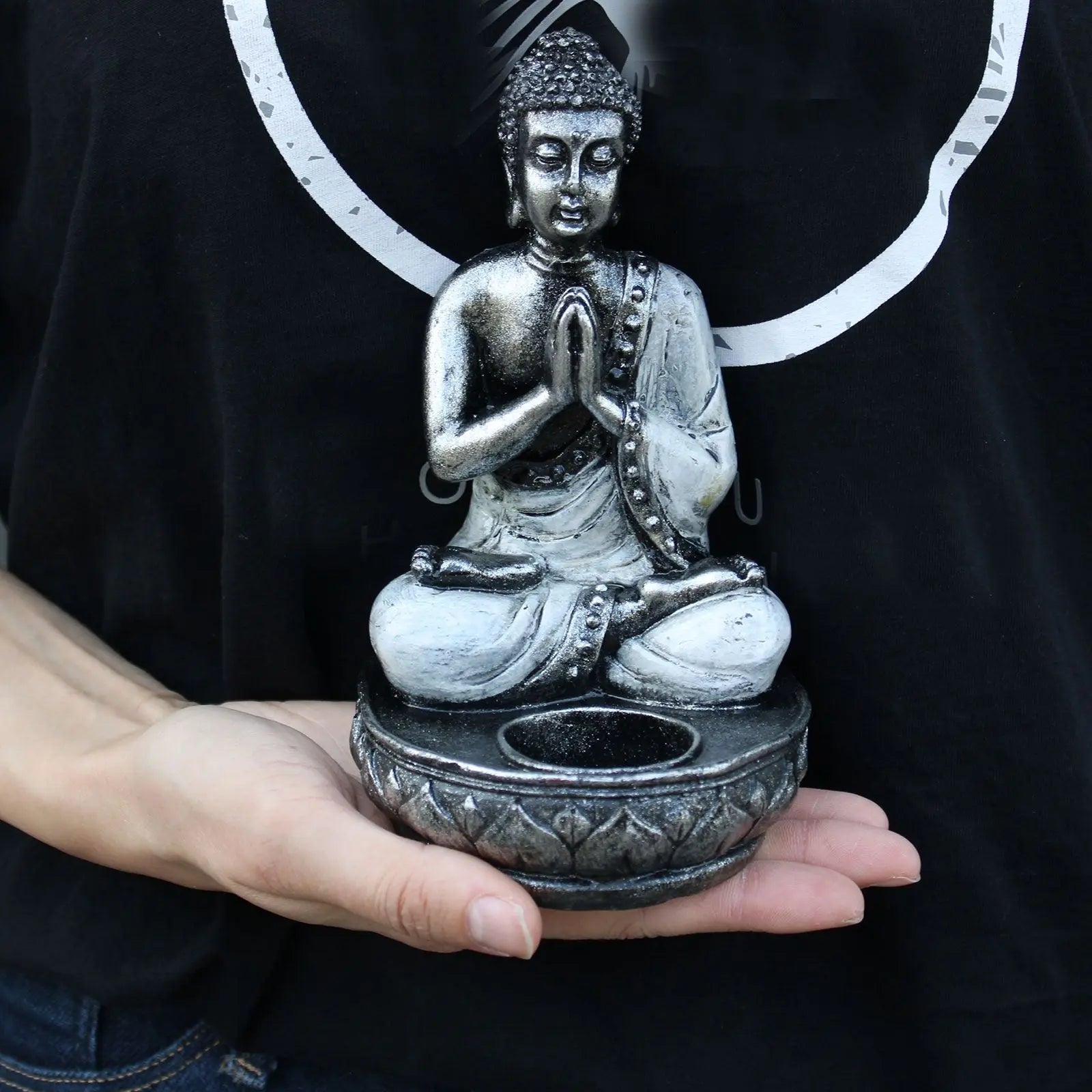 Person holding a hand-carved Buddha Candle Holder - White - Medium made of resin with detailed textures in a meditative pose on a lotus base designed to hold a candle.