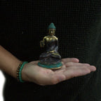 Med Hand Up Sitting Buddha resin statue with gold and turquoise accents held in a person's hand, showcasing detailed craftsmanship and serene expression.