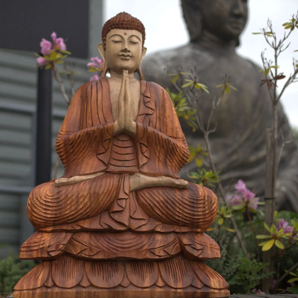 Hand Carved Buddha Statue - 80cm Welcome featuring intricate wooden craftsmanship, seated in meditation with hands in prayer, set against a garden backdrop with floral and stone elements.