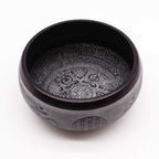 Earth Powder Singing Bowl - Om Five Buddha - 16cm featuring intricate engraved Buddha designs and traditional patterns on a dark metal surface for meditation and decor.