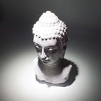 White Buddha bust statue illuminated by a soft spotlight on a dark background, showcasing intricate curls and serene facial features, Buddha Bust Lamp Lavender Crackle - Oval Stand.
