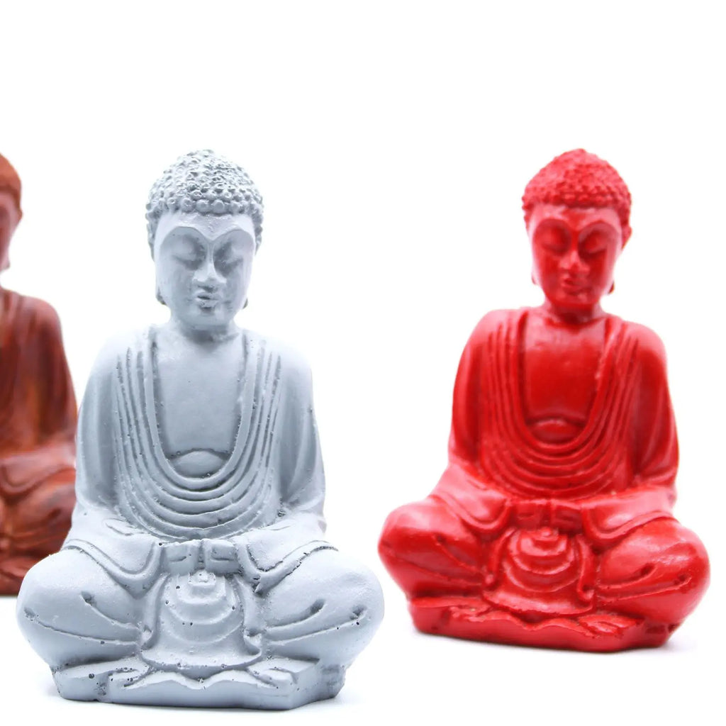 Three Matt Mini Buddha (Assorted Colours) statues in red, white, and terracotta, each depicting a serene seated Buddha in meditation pose with detailed drapery and textured hair.
