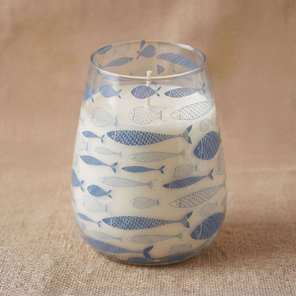 Tall Glass Jar Candles - Seabreeze featuring a clear glass container decorated with blue fish patterns, filled with white wax on a natural fabric surface.