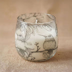 Medium Glass Jar Candles - Drawn by Flame featuring a delicate black and white illustration of two birds perched on a branch, surrounded by leaves and floral elements.