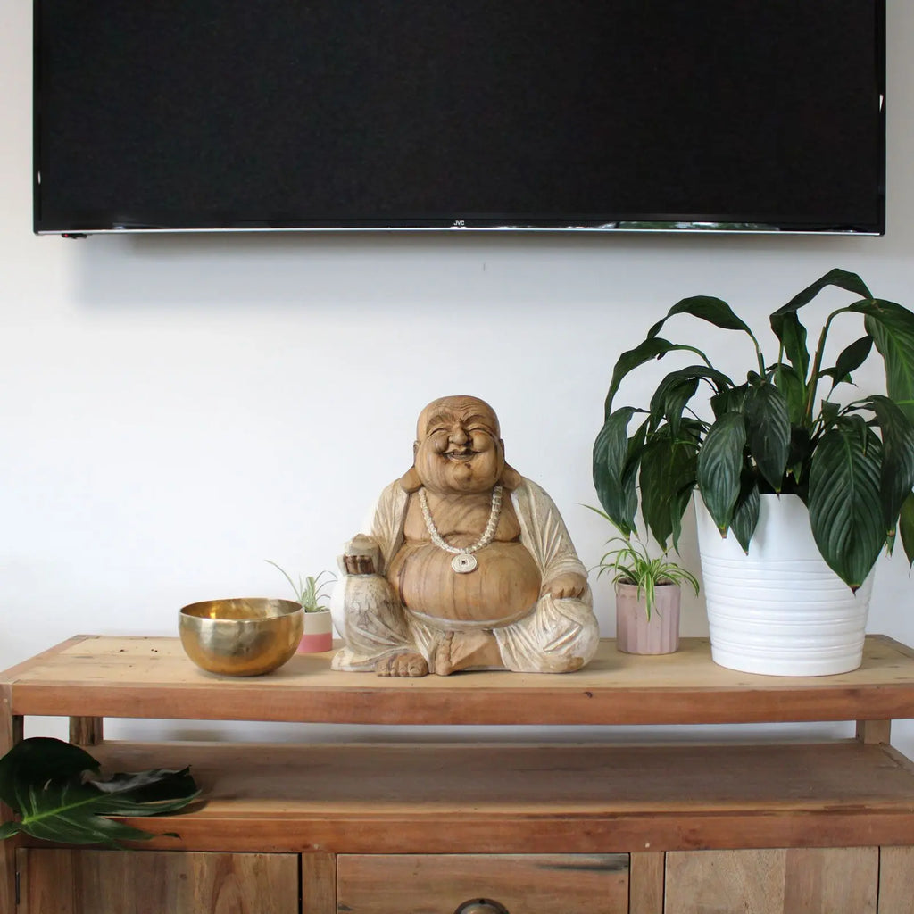 Happy Buddha - Whitewash 40cm statue displayed on a wooden shelf between two potted plants with a brass bowl, creating a serene Buddha decor centerpiece.