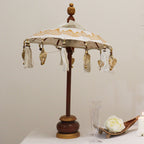 Decorative Bali Home Decor Parasol - Canvas - Gold Decor- 40cm with intricate gold patterns and hanging tassels, displayed on a wooden stand next to candles and glassware.