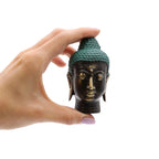 Hand holding a Small Antique Brass Buddha Head with green textured hair against a white background, showcasing a detailed brass Buddha decor piece.