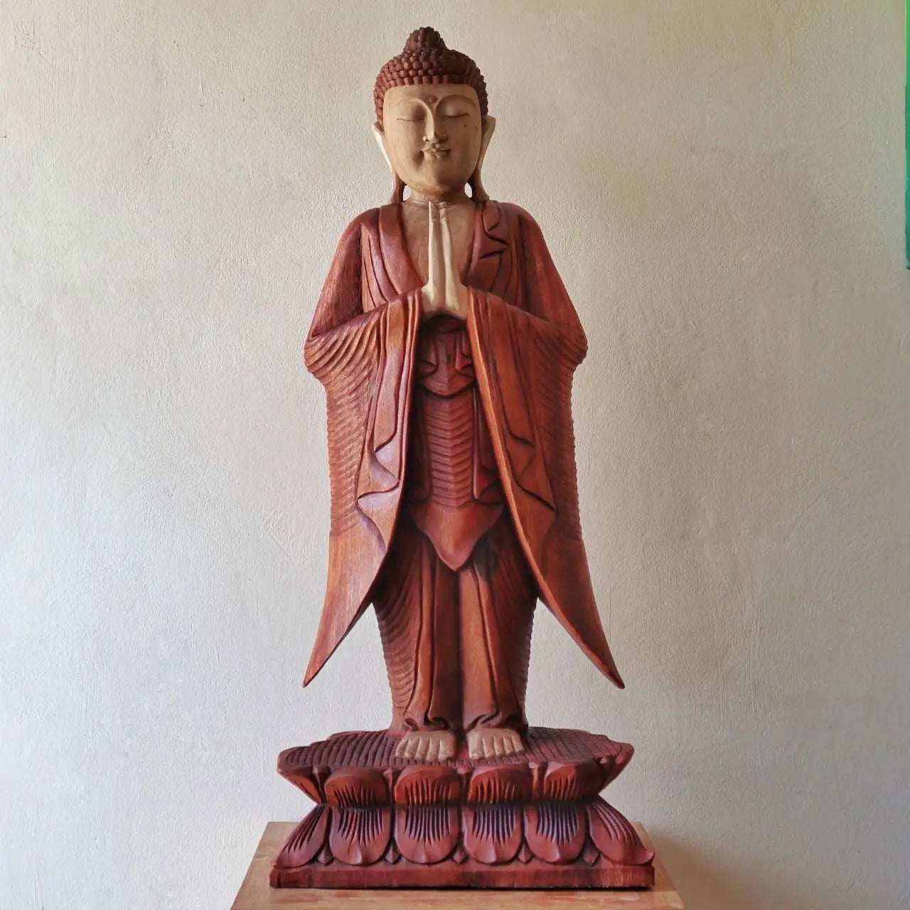 Buddha Statue Standing - 1m Welcome, a hand carved Buddha statue in reddish brown tones with detailed robes and serene facial expression, standing on a lotus base.