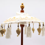 Bali Home Decor Parasol - Canvas - Gold Decor- 40cm with intricate gold patterns, hanging gold heart charms, and tassels on a wooden pole, showcasing elegant handcrafted detail.