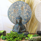 Buddha Feng Shui Set - Flower Mandala - Blue featuring a serene Buddha statue with hands in prayer position, set against a blue flower mandala backdrop surrounded by greenery.
