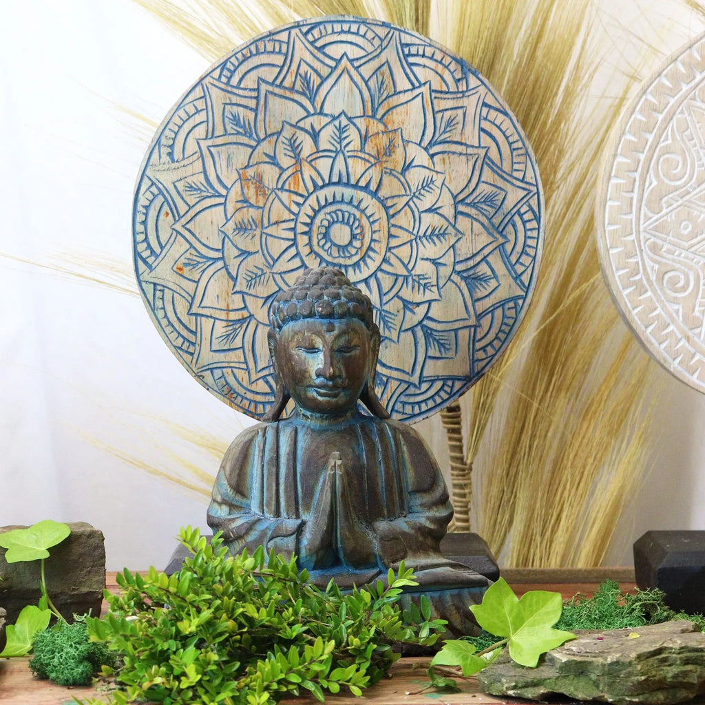 Buddha Feng Shui Set - Flower Mandala - Blue featuring a serene Buddha statue in meditation pose with a large blue floral mandala backdrop surrounded by natural greenery and stones.