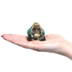 Small hand-held bronze and turquoise resin Buddha statue with smiling face, part of the Set of 3 - See No Evil etc - Buddha collection, displayed on an open palm.