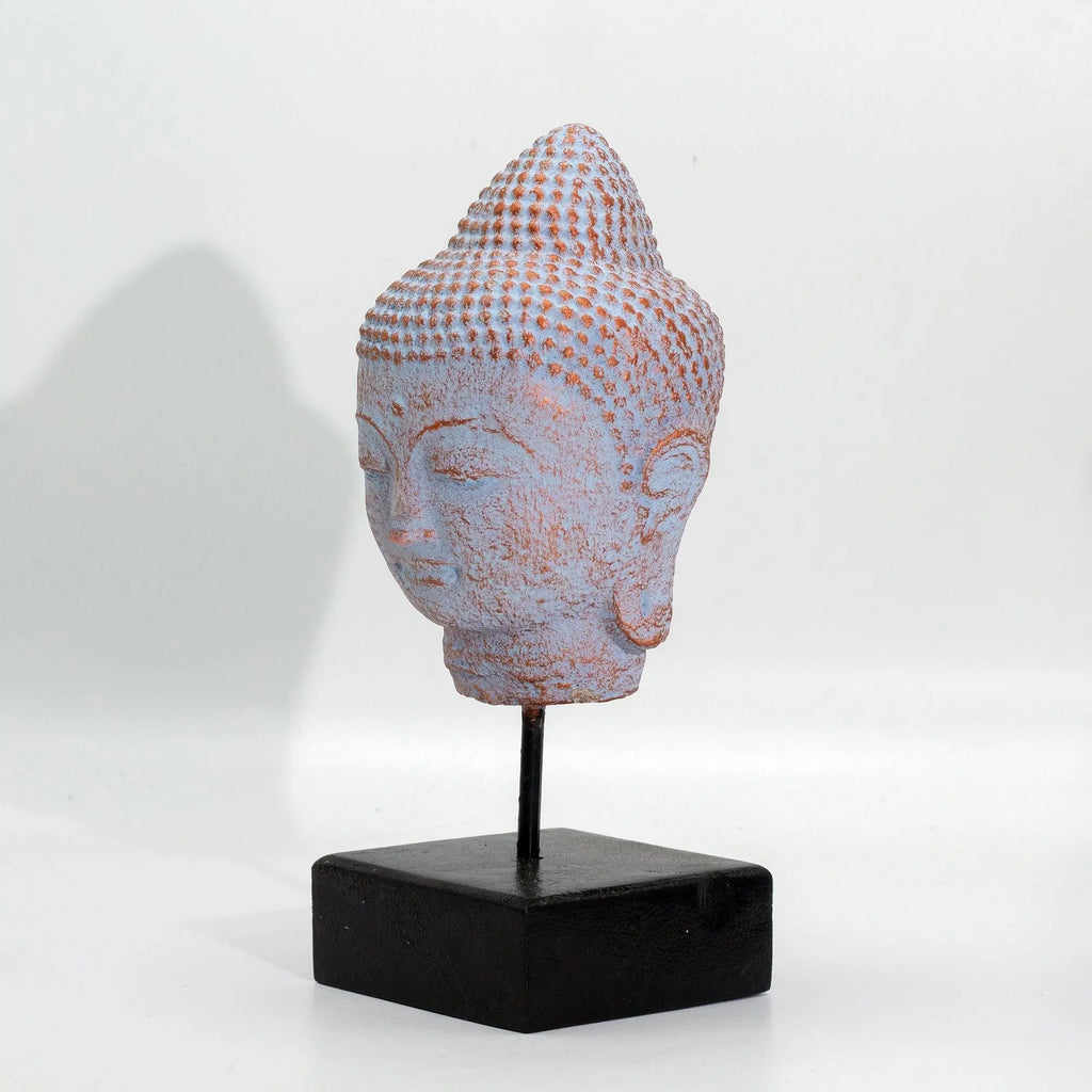 Stillness Buddha Head on Stand - Blue Copper displayed on a black square base, showcasing a textured blue copper finish with serene facial features and detailed hair curls.