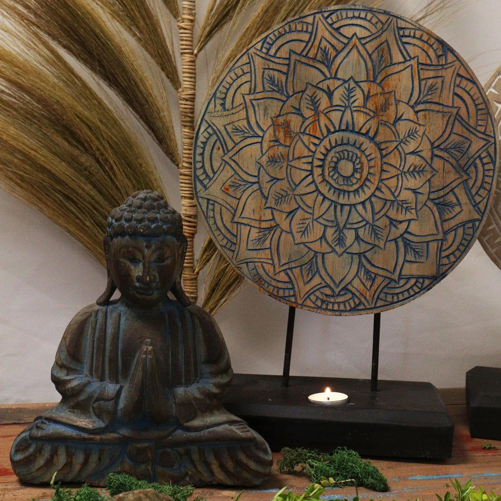Buddha Feng Shui Set - Flower Mandala - Blue featuring a serene hand carved Buddha statue in a meditative pose with a decorative blue flower mandala art piece on a black stand, surrounded by natural elements.