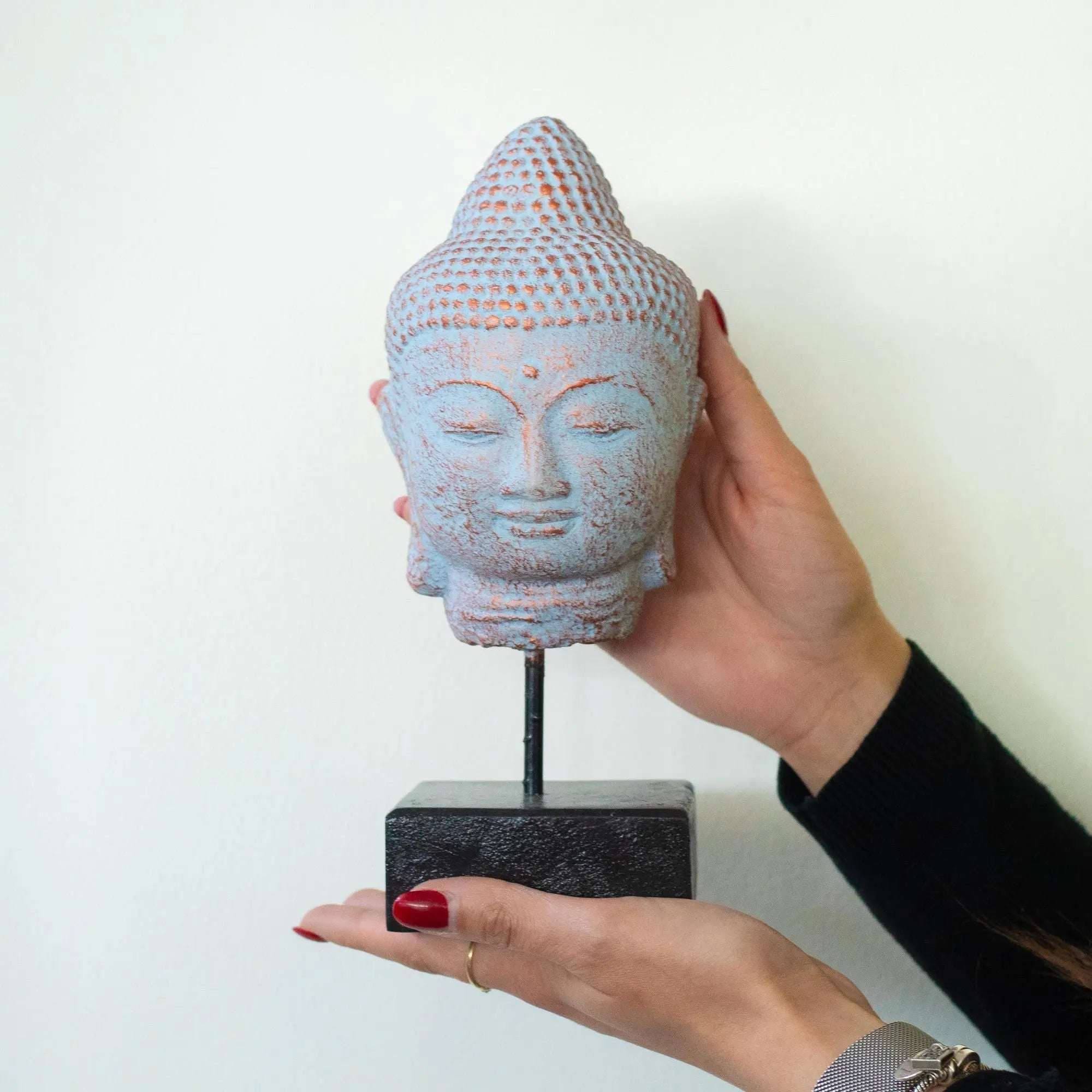 Stillness Buddha Head on Stand - Blue Copper displayed in hands, featuring a serene Buddha head with blue copper finish mounted on a black stand, ideal for Buddha decor.