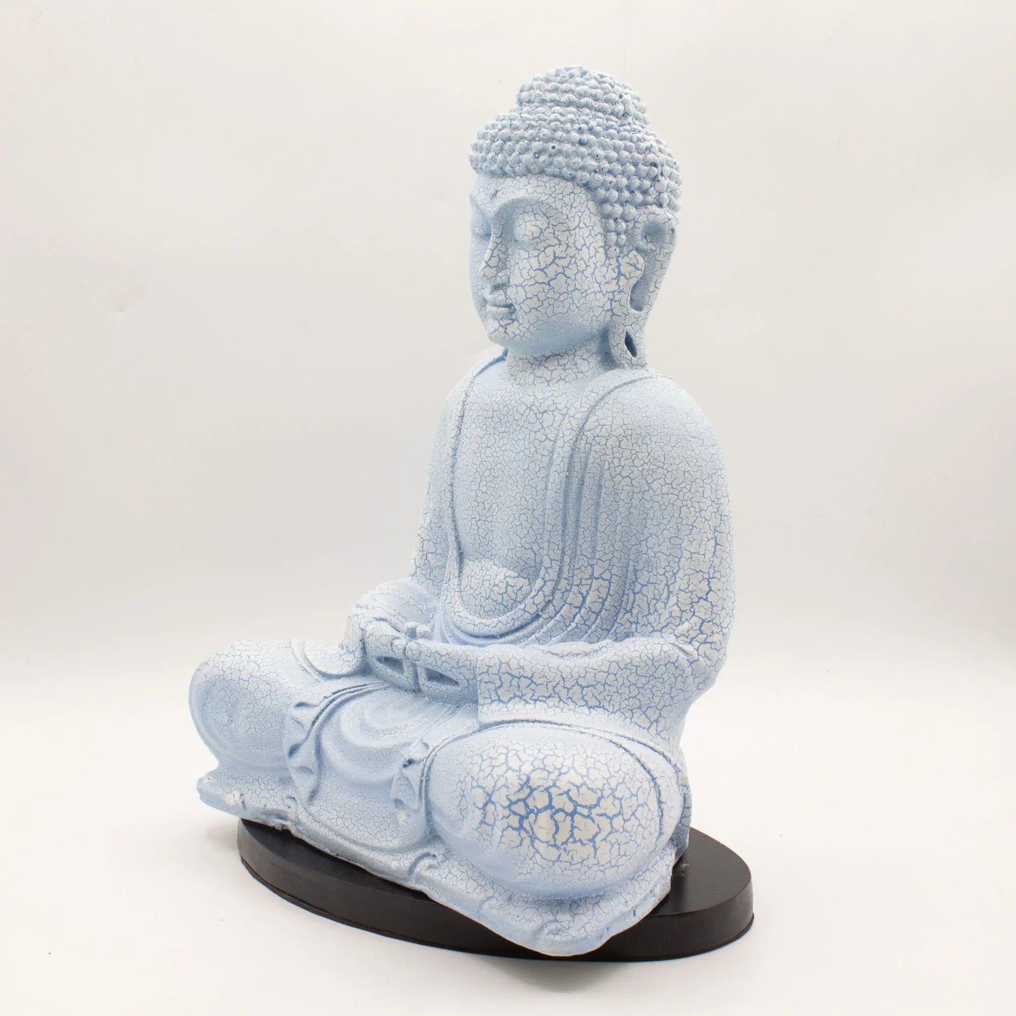 Meditation Buddha Lamp Sky Blue - Oval Stand features a serene, sky blue Buddha statue with crackled texture seated in a meditative pose on a sleek oval black stand, ideal for calming Buddha decor.