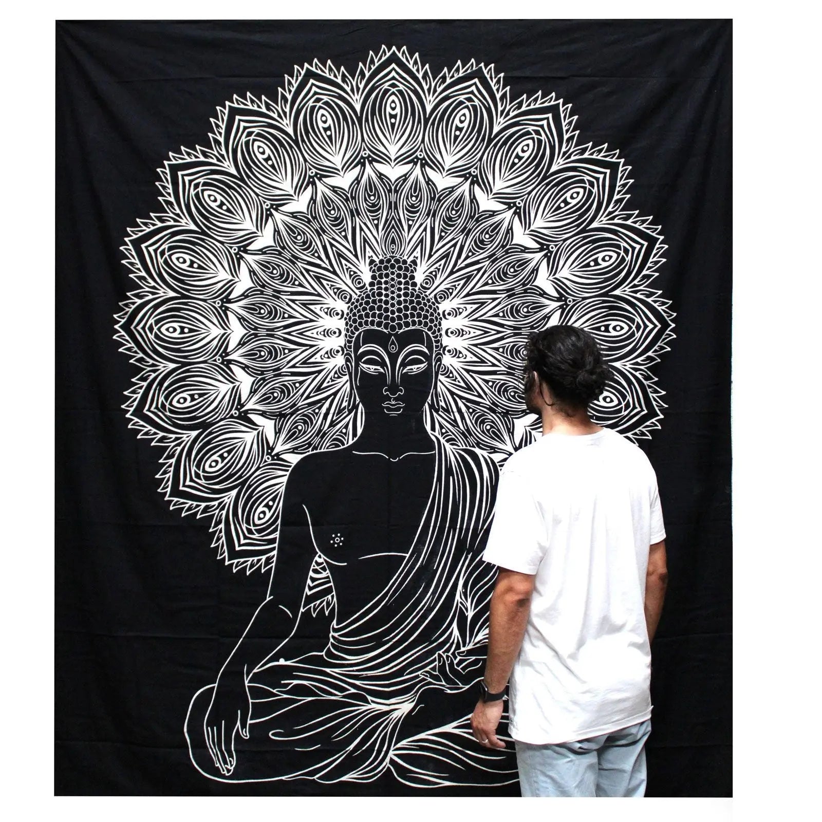 A man in a white t-shirt stands in front of a large black and white wall hanging featuring an intricate Buddha design with detailed mandala patterns, showcasing the B&W Double Cotton Bedspread + Wall Hanging - Buddha.